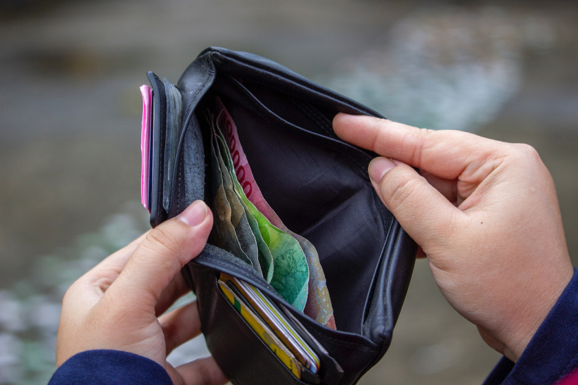 Seseorang membuka dompet berisi uang kertas Rupiah untuk ilustrasi arus kas dan transaksi keuangan Kasair POS