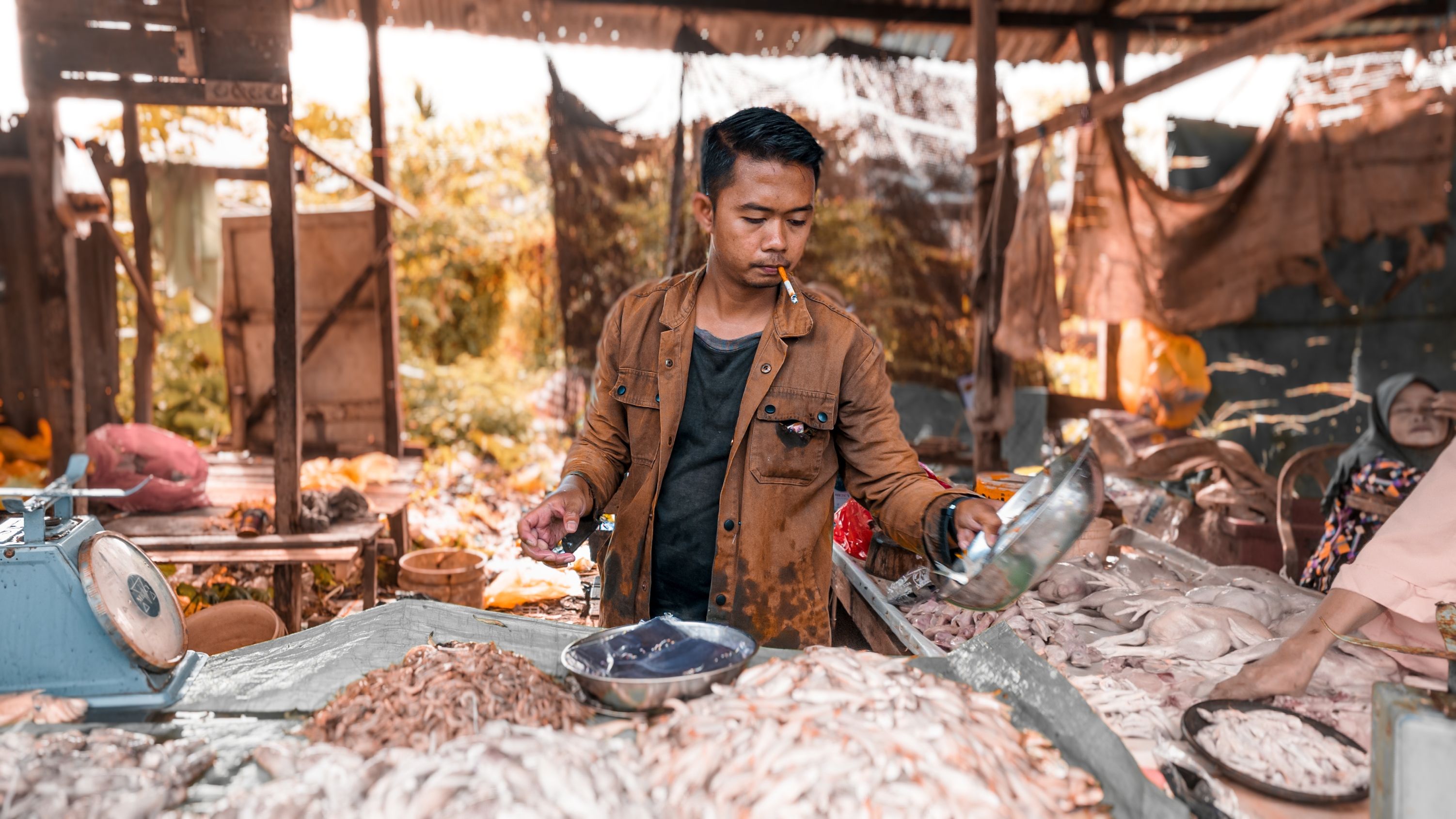 pedagang-ikan Seorang pedagang pria melayani pembeli di lapak jualan ikan dan bahan pangan pasar tradisional.