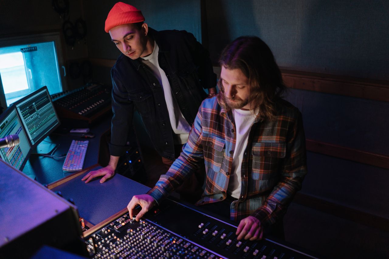 Dua orang mengoperasikan peralatan audio dalam studio rekaman