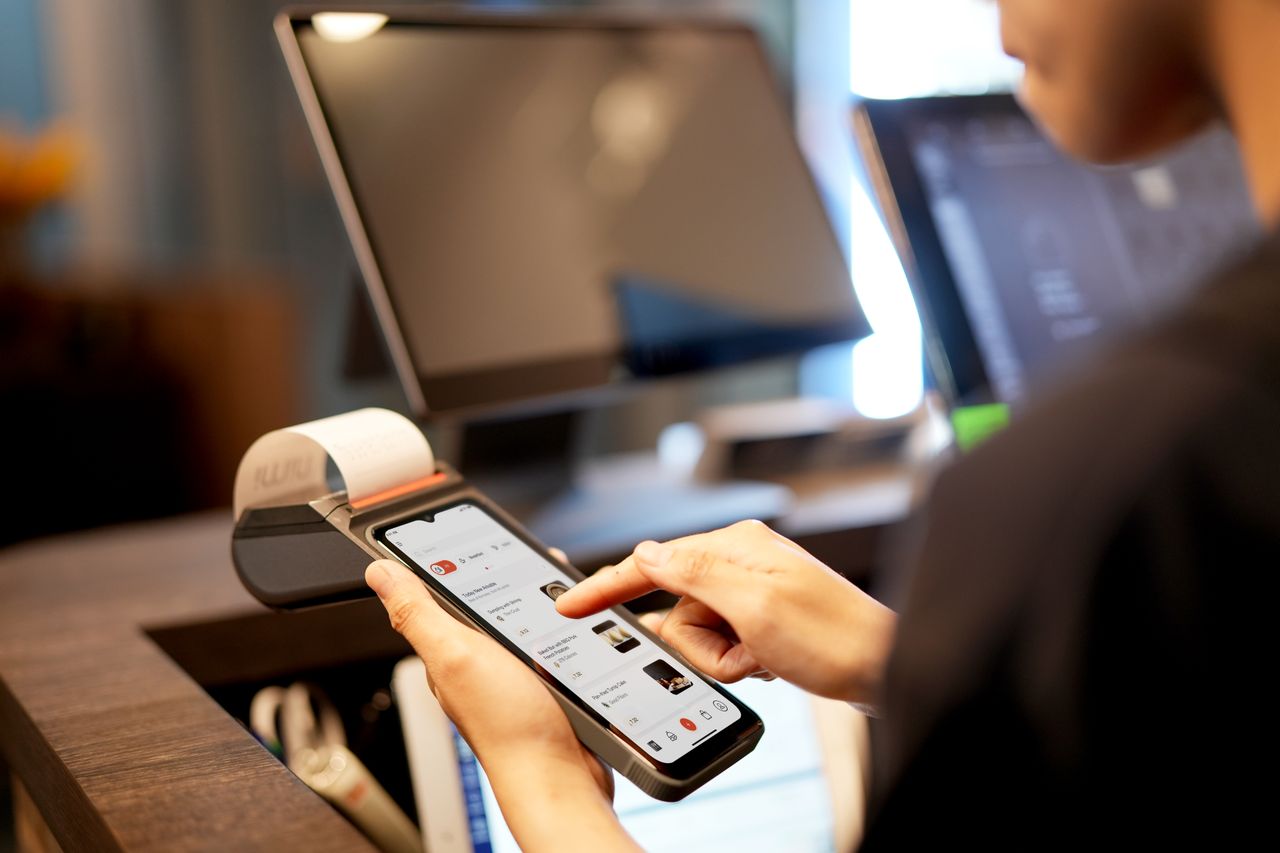 Seseorang menggunakan smartphone pada sistem kasir digital di toko