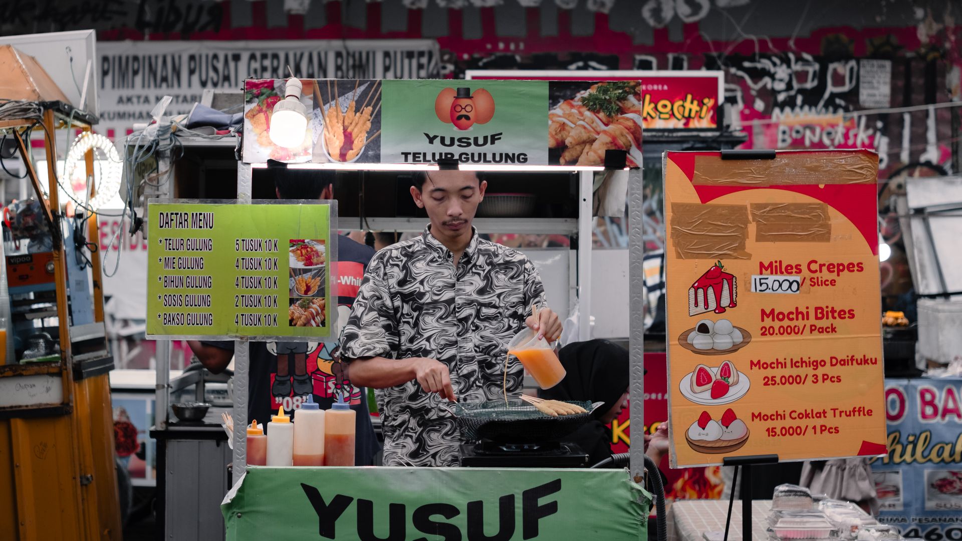 Yusuf-Teh-Gulung-Jajanan-Street-Food-Mochi-CrepesPenjual Yusuf Teh Gulung sedang menyiapkan jajanan street food mochi crepes