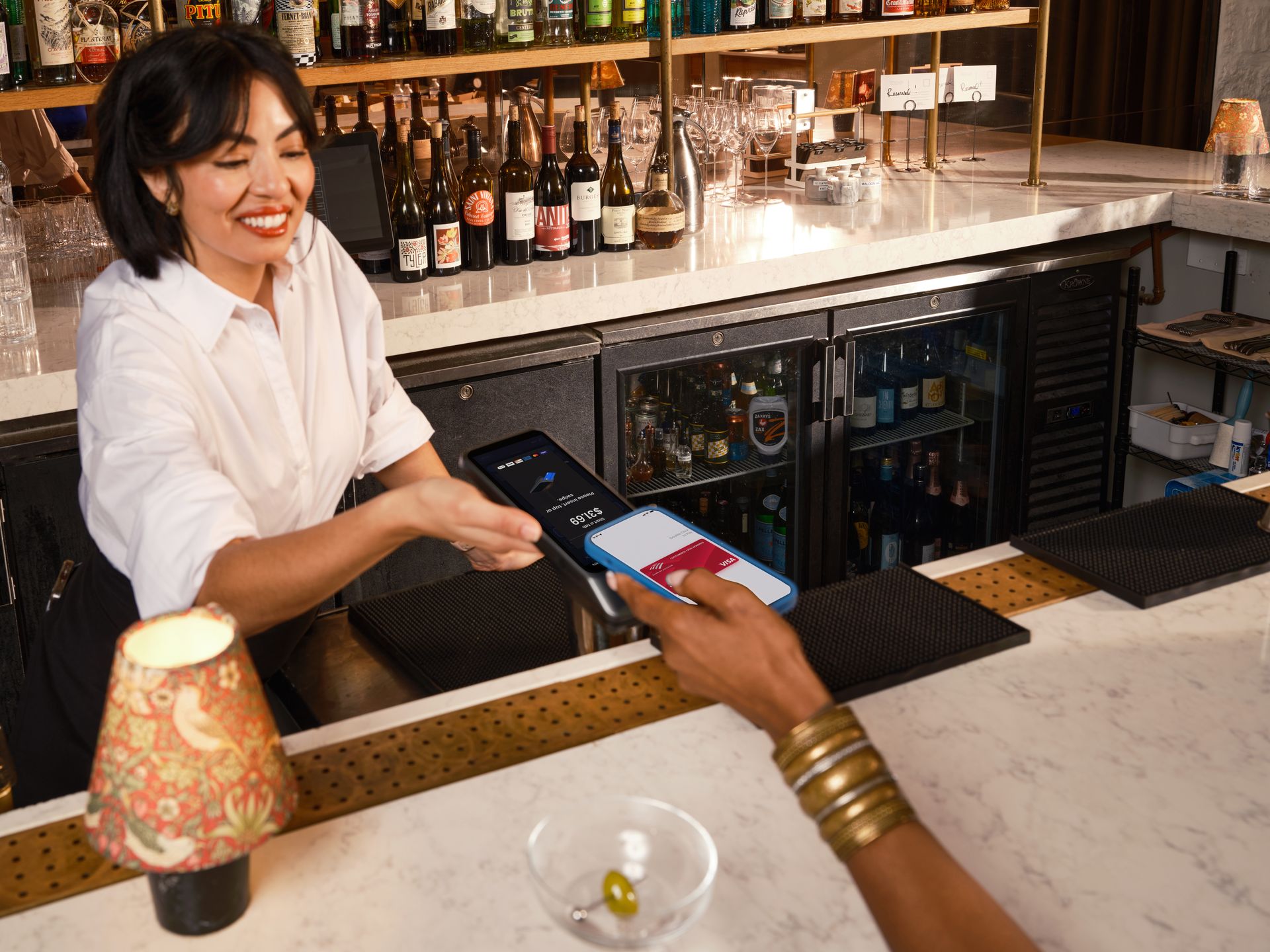 Barista melayani transaksi pembayaran contactless menggunakan ponsel pelanggan ke mesin POS pintar Kasair POS di bar