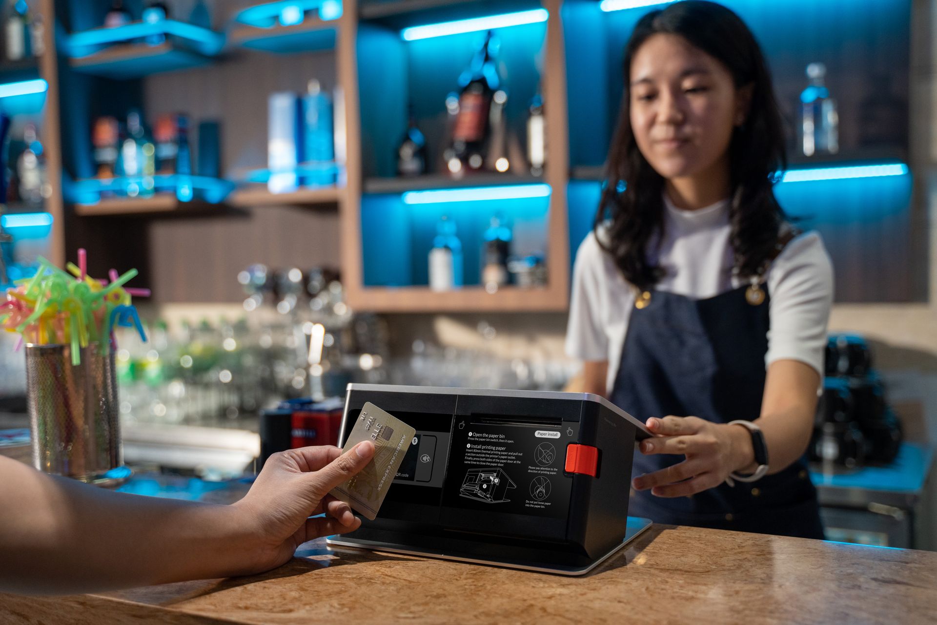 Pelanggan membayar menggunakan kartu di mesin POS kasir kafe yang dilayani barista