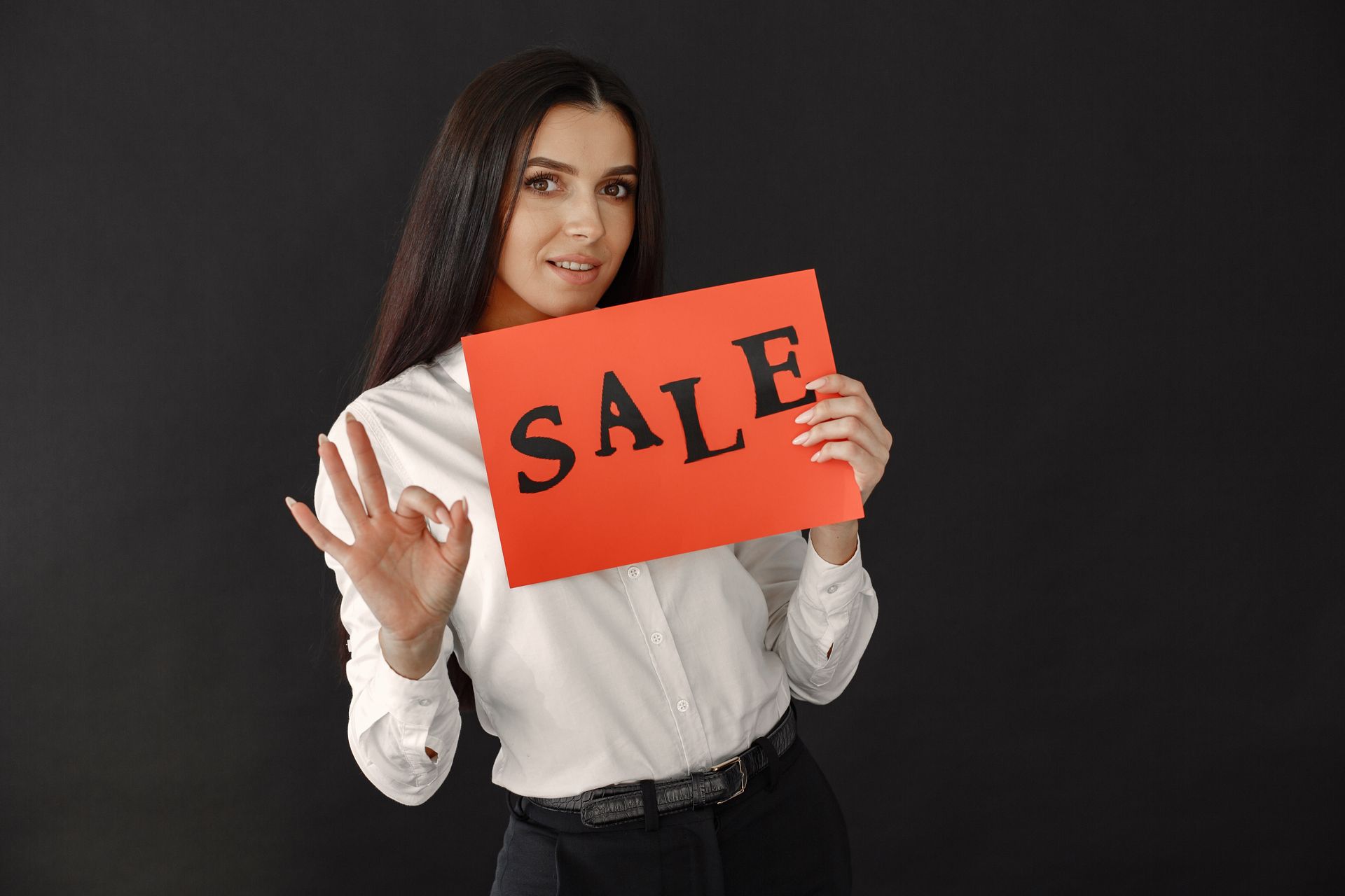 Wanita-Memegang-Tanda-Promo-Diskon-Sale-Toko Wanita berpenampilan profesional memegang papan bertuliskan sale dan menunjukkan gestur ok