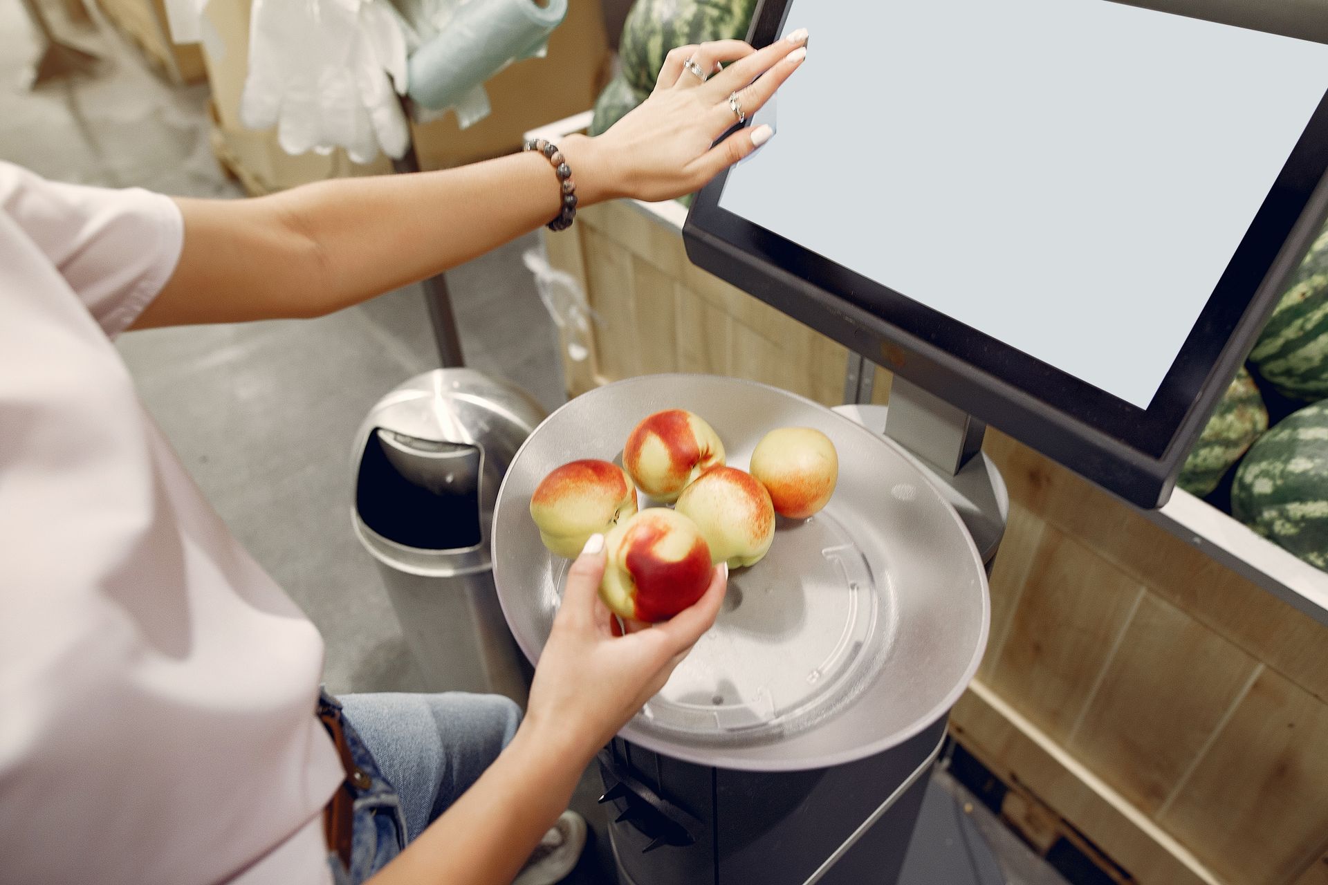 Seseorang menimbang buah apel di atas timbangan digital berlayar sentuh di supermarket