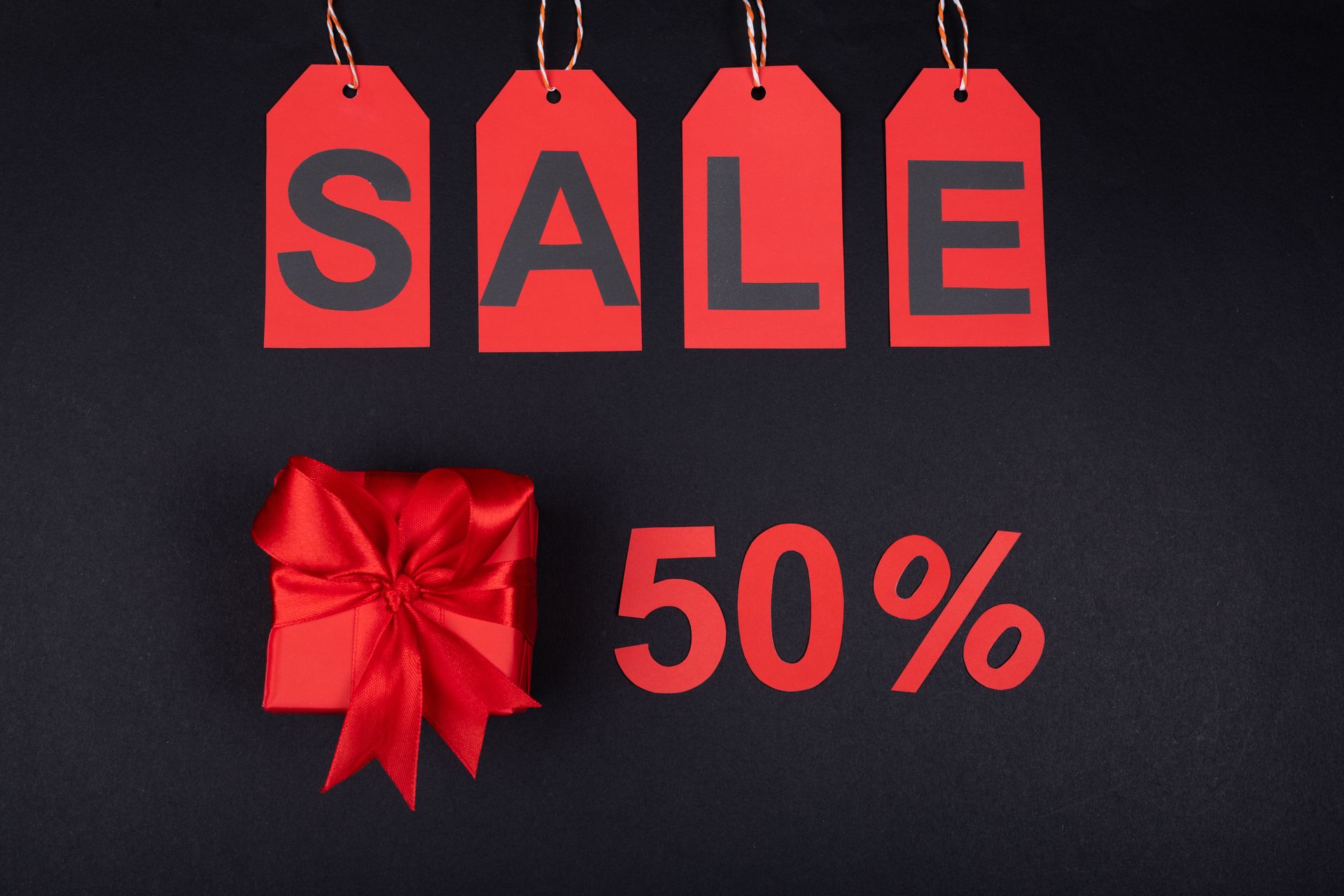 Label harga bertuliskan SALE 50 persen dan kado merah sebagai ilustrasi fitur kelola diskon dan promosi di aplikasi Kasair POS