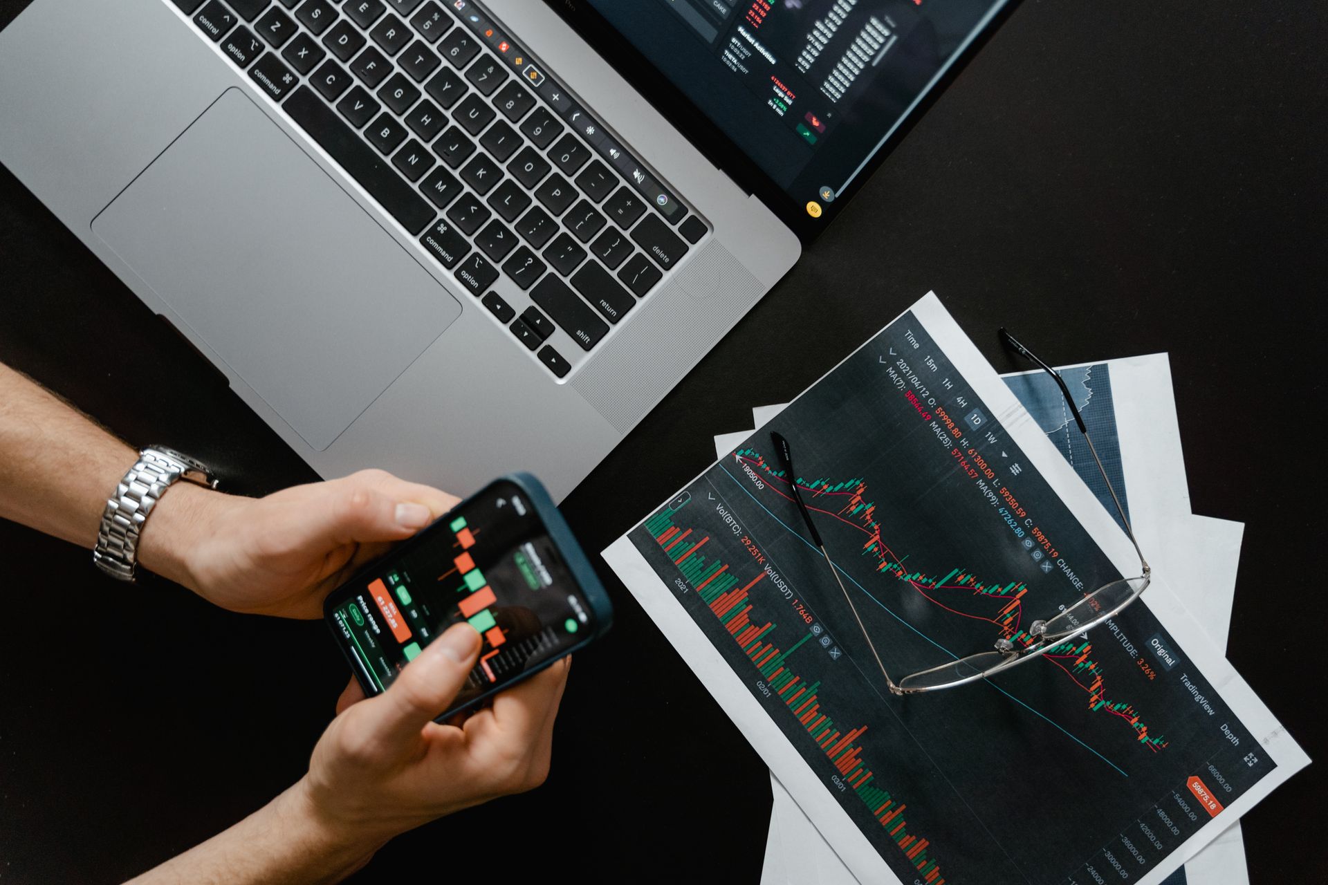 sistem-pos-dalam-bisnis-properti-dan-investasi-kasair Seseorang memantau grafik analisis investasi dan laporan transaksi properti melalui smartphone dan laptop berbasis Kasair POS