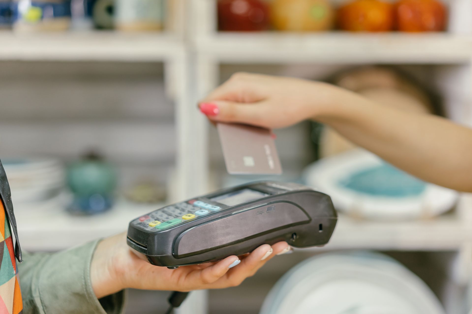 Pelanggan mengarahkan kartu pembayaran di atas mesin EDC terminal kasir untuk transaksi non-tunai contactless di toko