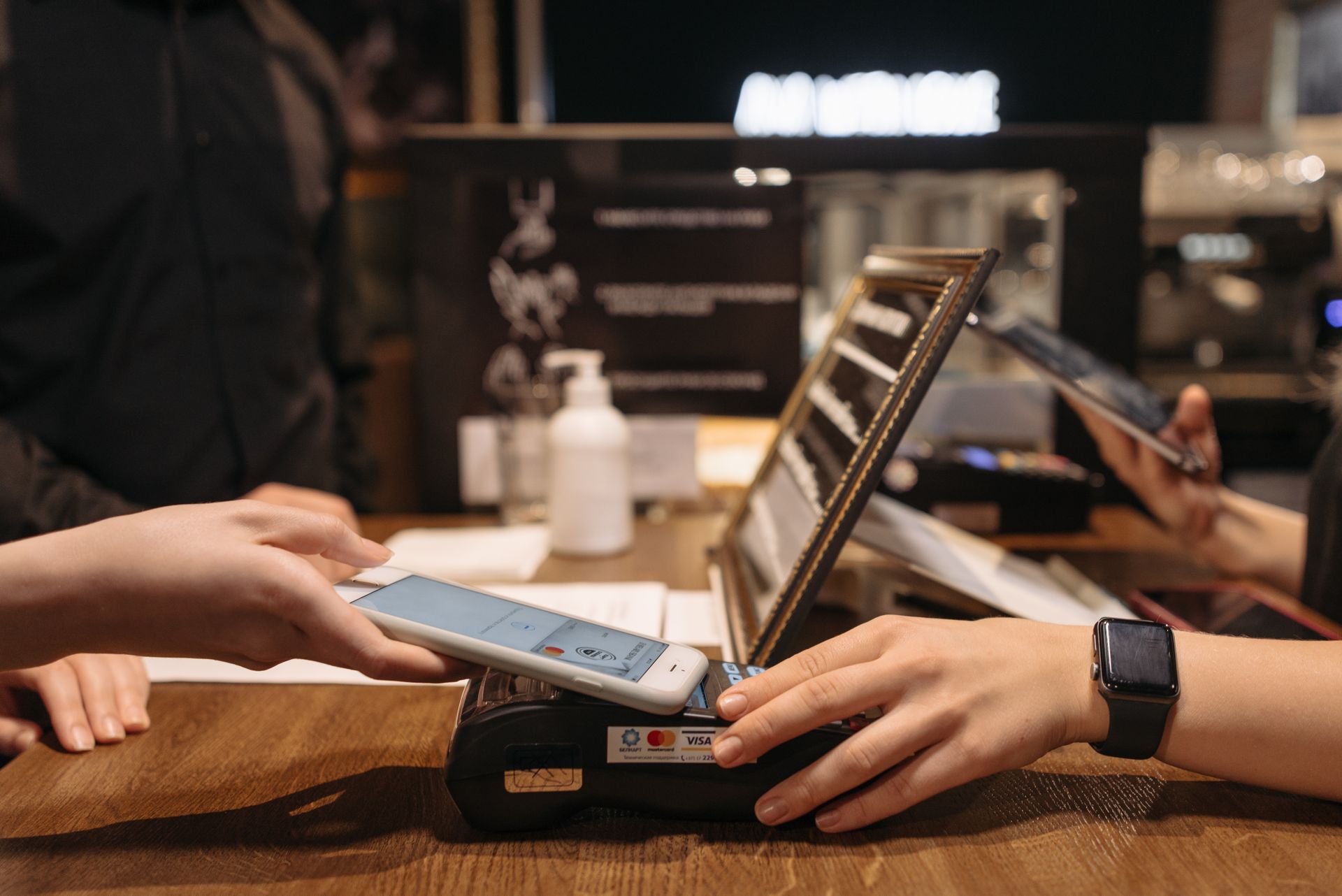 Pembayaran Digital Smartphone Contactless di Terminal Kasir POS Pelanggan menempelkan smartphone di atas mesin EDC terminal kasir untuk melakukan transaksi pembayaran digital contactless non-tunai di meja counter