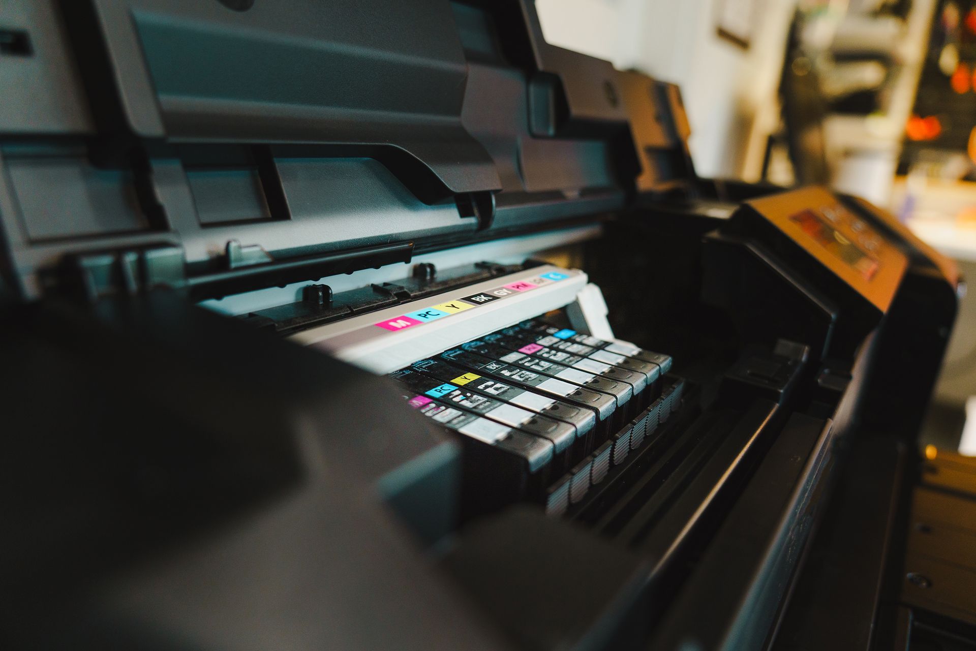 Tampilan jarak dekat jajaran katrid tinta warna CMYK di dalam mesin printer inkjet profesional usaha percetakan digital