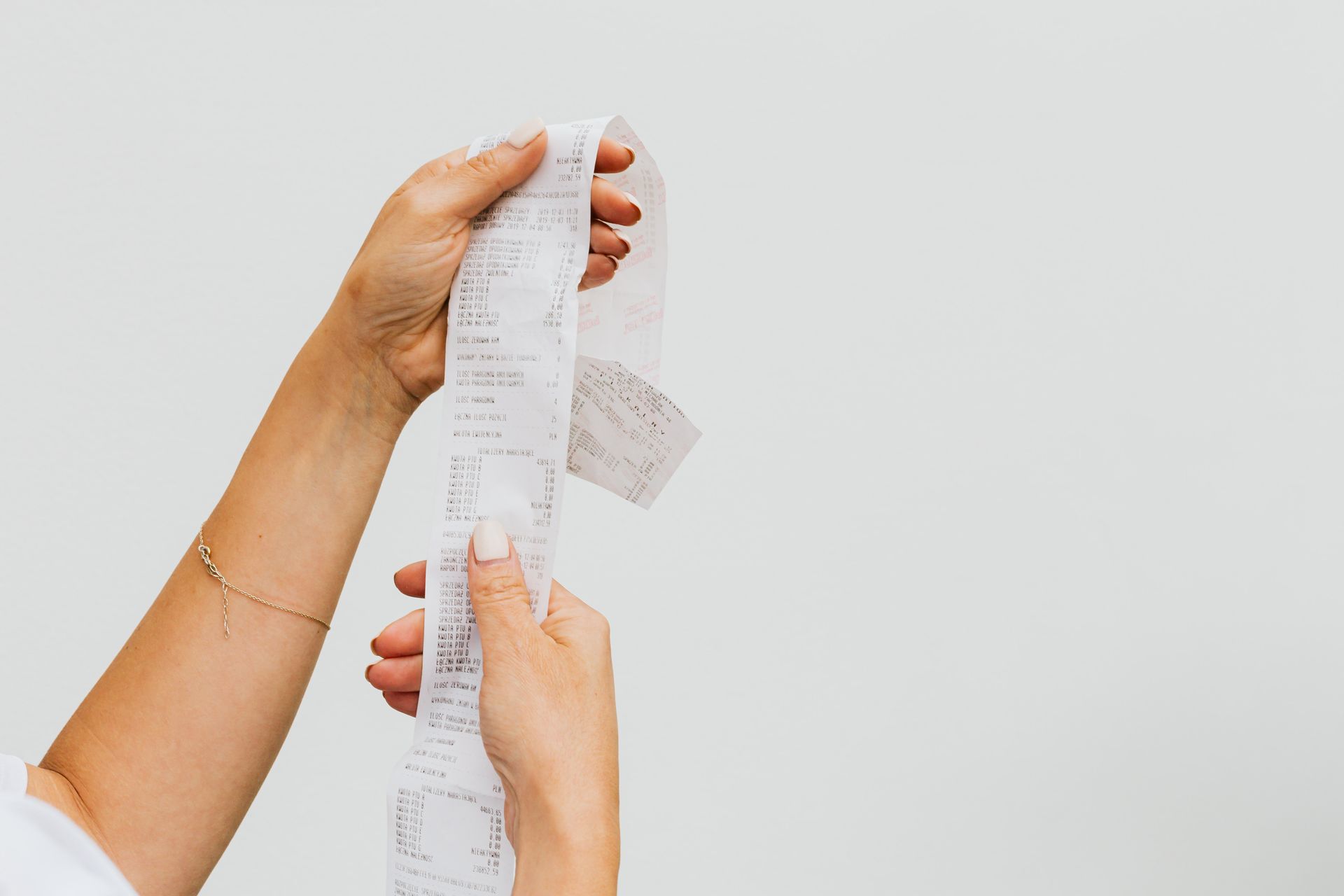 memilih-kertas-kasir-yang-cocok-untuk-bisnis-kasair Tangan memegang cetakan struk bukti pembayaran dari mesin pencetak kertas kasir terintegrasi Kasair POS