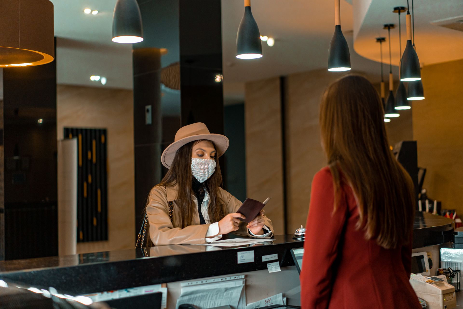 Tamu hotel memperlihatkan dokumen identitas saat proses check-in dan verifikasi pembayaran kasir di meja resepsionis berbasis Kasair POS