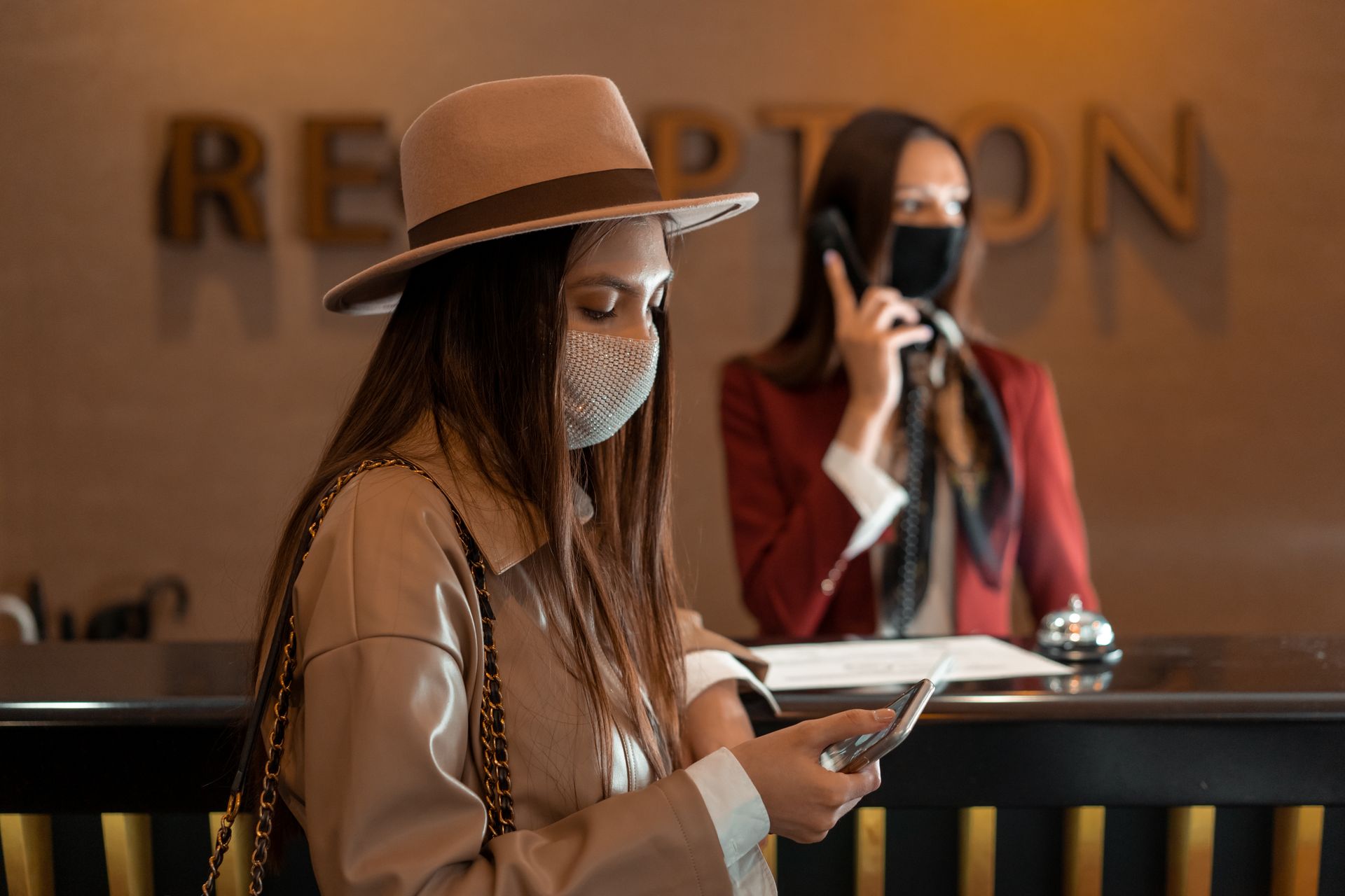 Tamu hotel menggunakan smartphone untuk pembayaran nirkontak dan reservasi di meja resepsionis terintegrasi Kasair POS