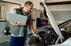 aplikasi-kasir-bengkel-otomotif-kasair Mekanik bengkel otomotif menggunakan laptop dan sistem Kasair POS untuk diagnosa dan pencatatan servis